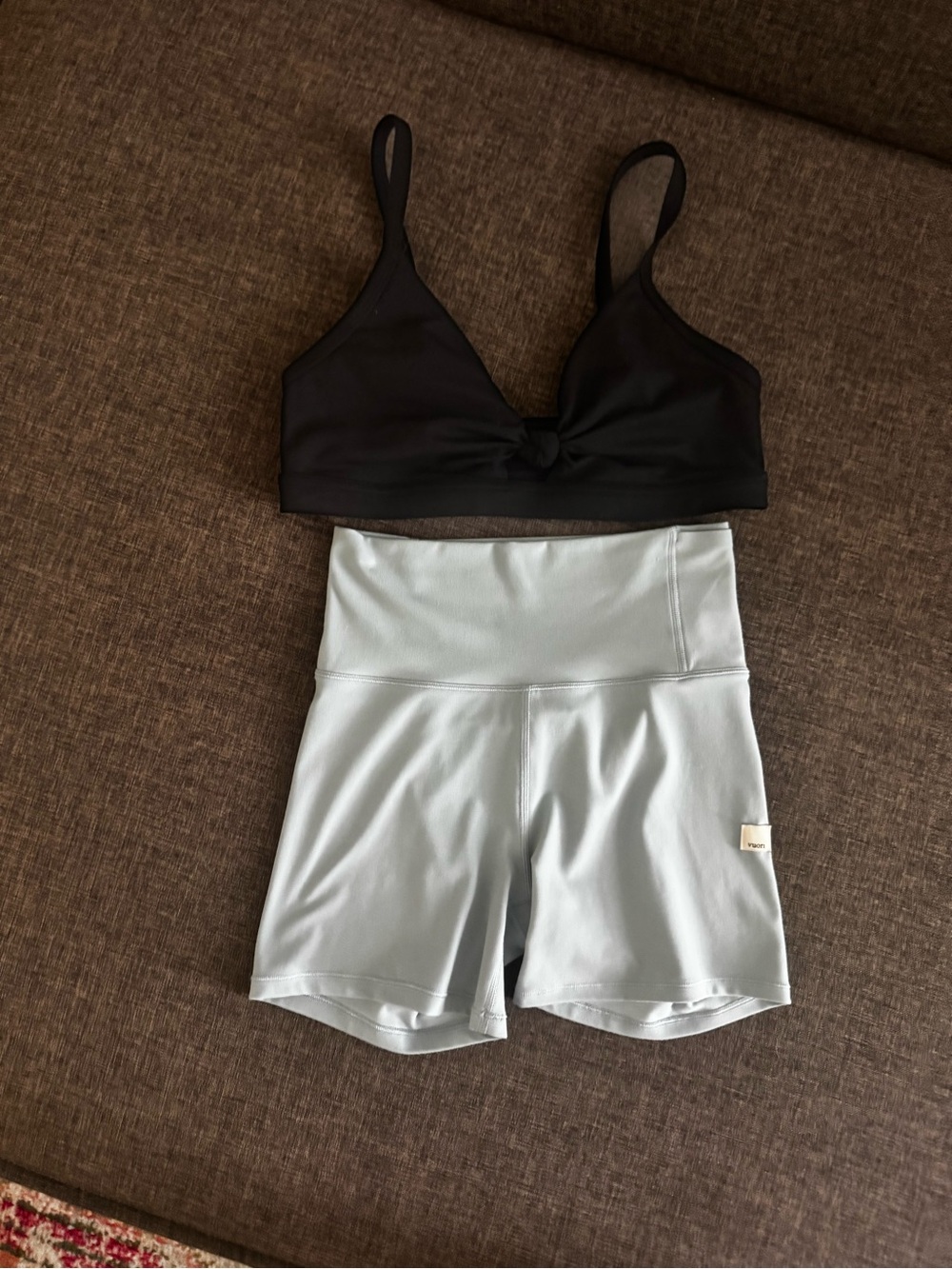 Black sports bra (SPIRITUAL GANGSTER) and light blue athletic shorts (VUORI) set